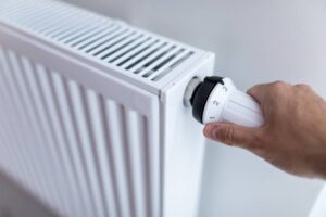 woman,holding,temperature,knob,of,heating,radiator